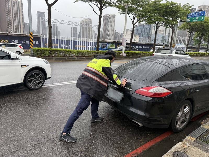 黑色保时捷雨天在南桃园交流道大兴西路往桃园方向抛锚，员警巡逻经过帮忙推车解围，过程中有热心货车司机加入，让后方回堵的车流赶紧纾解。（记者郑淑婷翻摄）